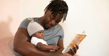 Man reading to newborn baby