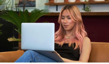 A transfeminine person using a laptop at work